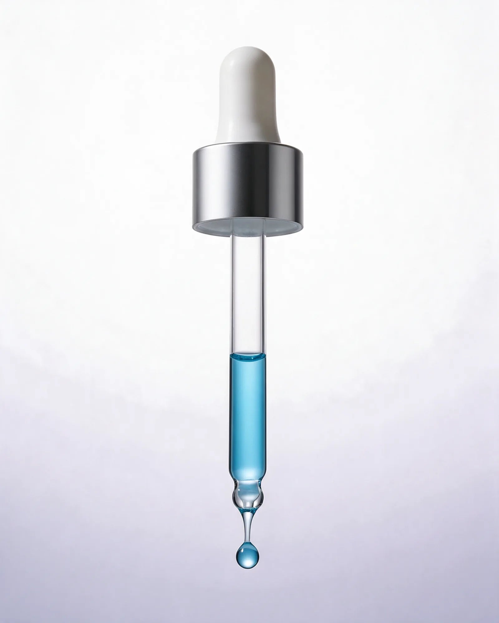 A single drop of serum at the tip of the glass dropper