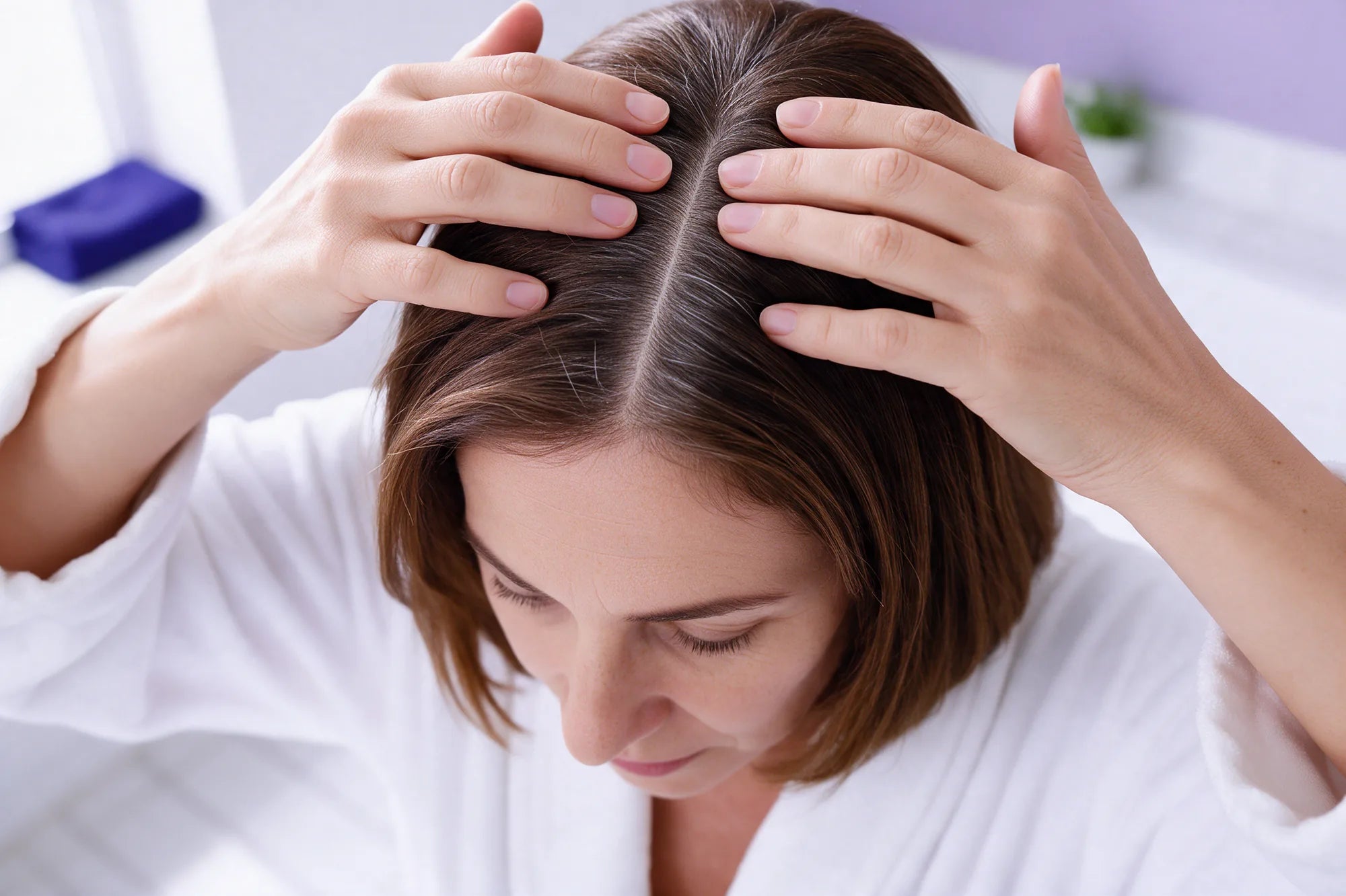 Fingertips massaging the scalp on both sides of a part