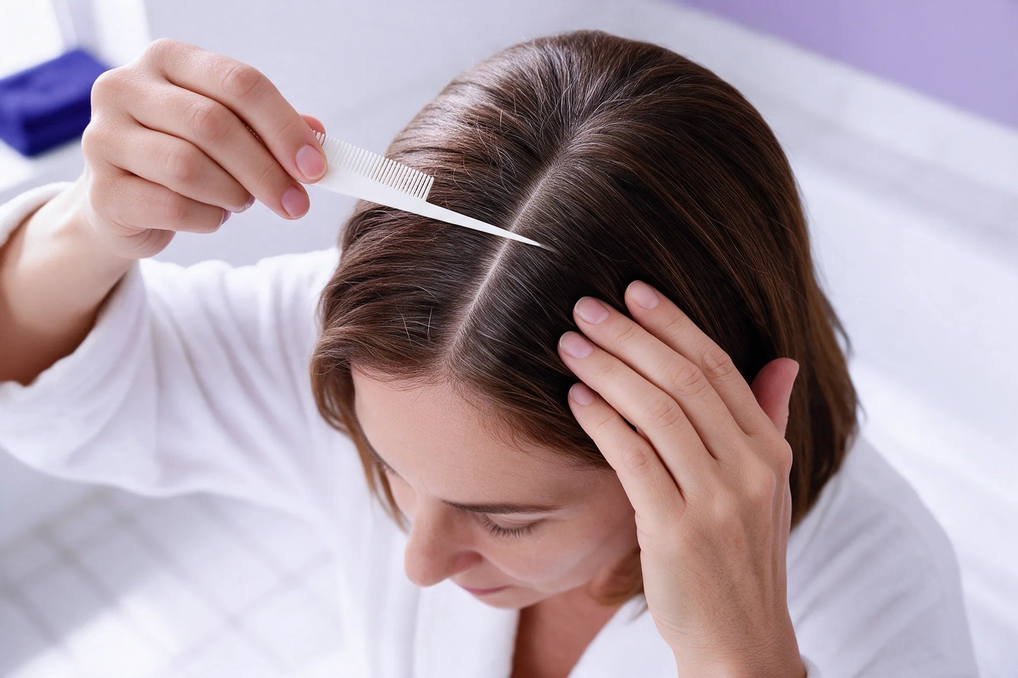 A woman parting her hair with a fine comb